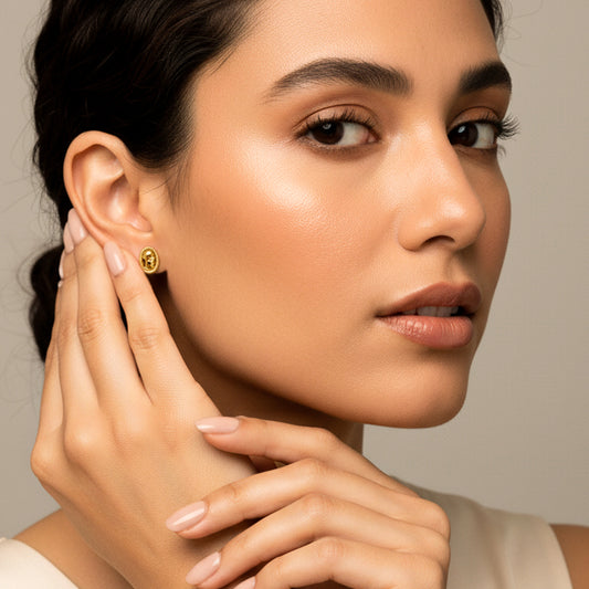 Oreja de modelo usando un topito en forma de ángel rezando en oro amarillo de 18 quilates de Joyería Caracas.