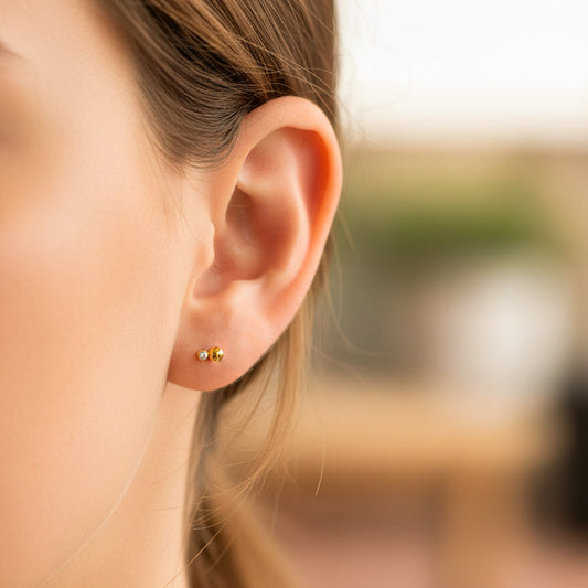 Oreja de modelo usando un topito en forma de hormiga en oro amarillo de 18 quilates con cristal de color blanco de Joyería Caracas.