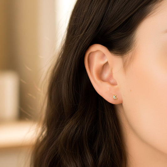 Oreja de modelo usando un topito en forma de caballo en oro amarillo de 18 quilates con cristales de color blanco de Joyería Caracas.