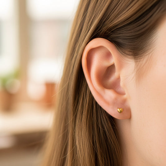 Oreja de modelo usando un topito en forma de corazón acanalado en oro amarillo de 18 quilates de Joyería Caracas.