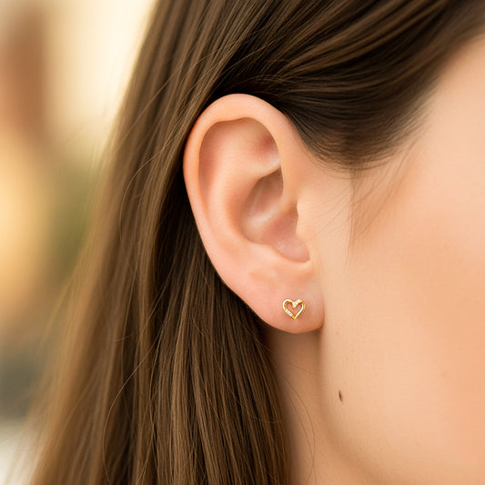 Oreja de modelo usando un topito en forma de corazón en oro amarillo de 18 quilates con cristales de color blanco de Joyería Caracas.