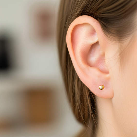 Oreja de modelo usando un topito en forma de corazón en oro amarillo de 18 quilates con cristal en el centro de Joyería Caracas.
