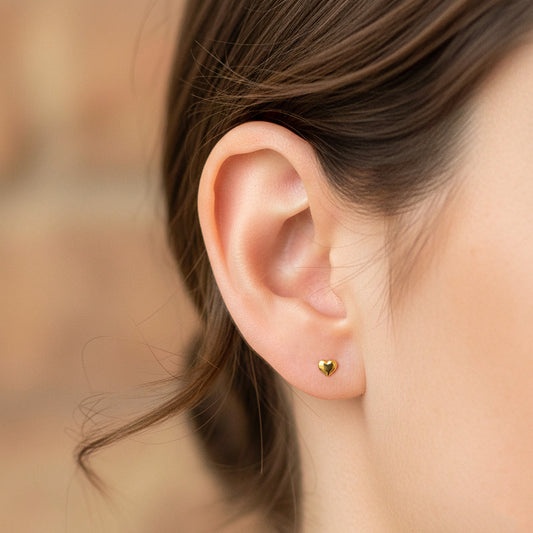 Oreja de modelo usando un topito en forma de corazón en oro amarillo de 18 quilates de Joyería Caracas.