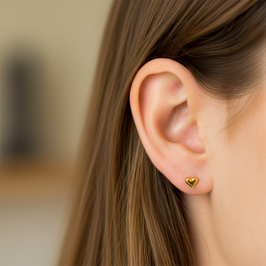Oreja de modelo usando un topito en forma de corazón en oro amarillo de 18 quilates de Joyería Caracas.