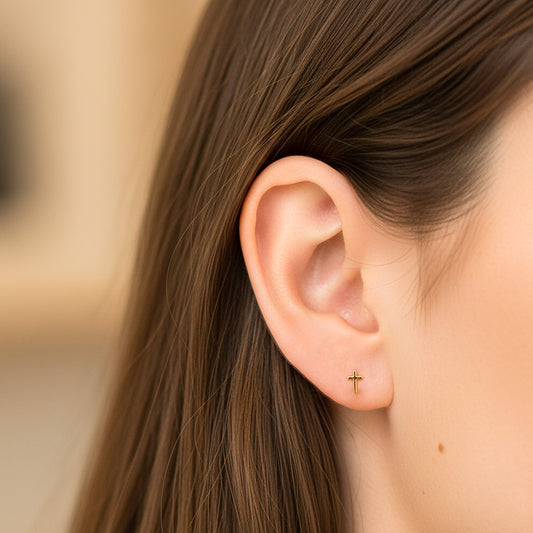 Oreja de modelo usando un topito en forma de cruz en oro amarillo de 18 quilates de Joyería Caracas.