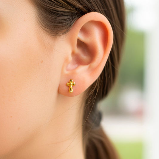 Oreja de modelo usando un topito en forma de cruz con cristo en oro amarillo de 18 quilates de Joyería Caracas.