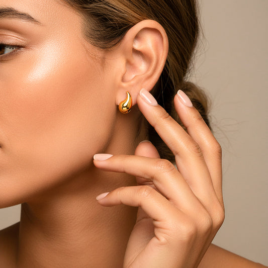 Oreja de modelo usando un topito en forma de gota en oro amarillo de 18 quilates de Joyería Caracas.