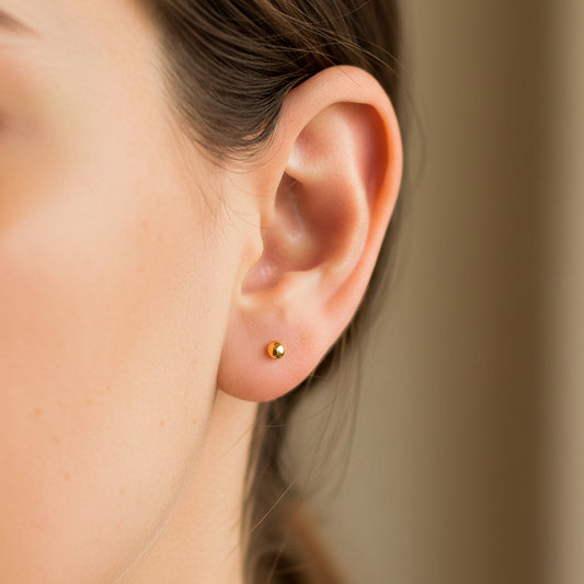 Oreja de modelo usando un topito de esfera lisa en oro amarillo de 18 quilates de Joyería Caracas.