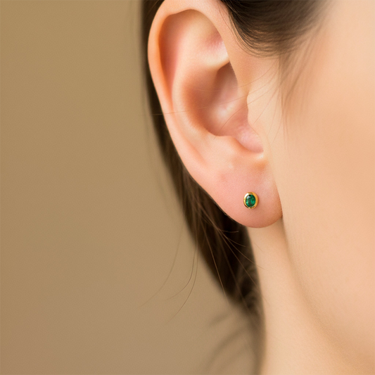 Oreja de modelo usando un topito en forma ovalada en oro amarillo de 18 quilates con Esmeralda de la misma forma de Joyería Caracas.