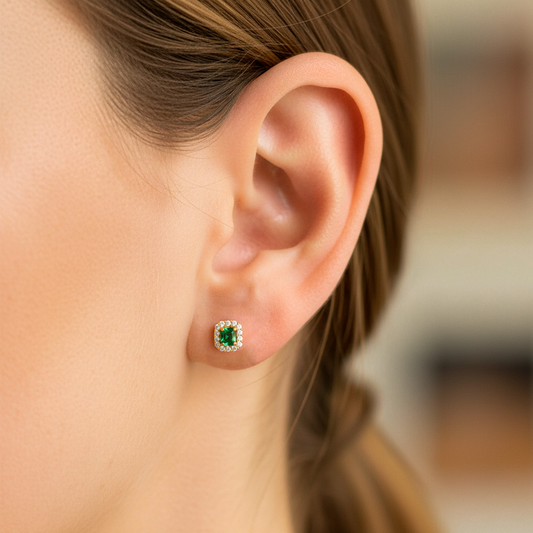 Oreja de modelo usando un topito en oro amarillo de 18 quilates con Esmeralda y cristales de color blanco de Joyería Caracas.