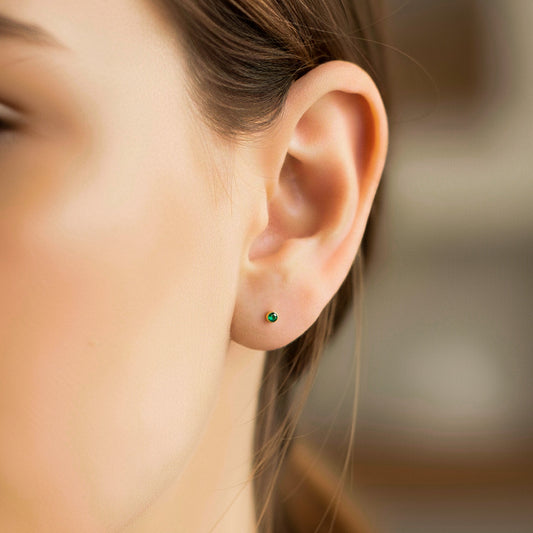 Oreja de modelo usando un topito biselado en oro amarillo de 18 quilates con Esmeralda circular de Joyería Caracas.