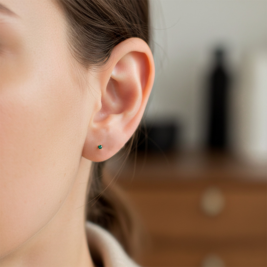 Oreja de modelo usando un topito en oro amarillo de 18 quilates con Esmeraldas de Joyería Caracas.