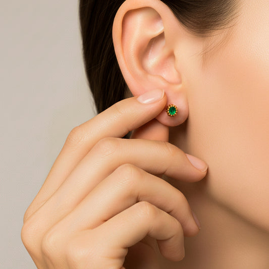 Oreja de modelo usando un topito en oro amarillo de 18 quilates con Esmeralda de Joyería Caracas.