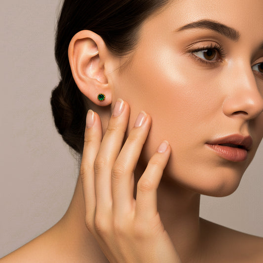 Oreja de modelo usando un topito empalillado en oro amarillo de 18 quilates con Esmeralda redonda de Joyería Caracas.