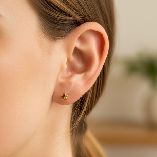 Oreja de modelo usando un topito en forma de estrella en oro amarillo de 18 quilates de Joyería Caracas.