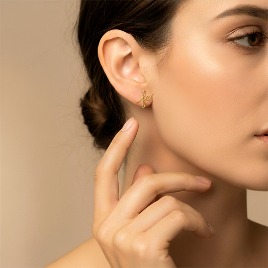 Oreja de modelo usando un topito con la palabra fe en oro amarillo de 18 quilates de Joyería Caracas.