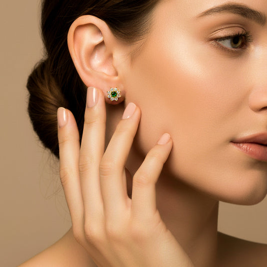 Oreja de modelo usando un topito en forma de flor en oro amarillo de 18 quilates con cristal de color verde y blancos alrededor de Joyería Caracas.