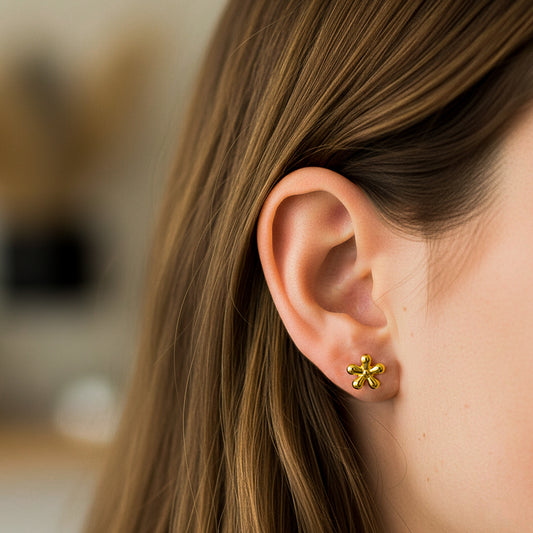 Oreja de modelo usando un topito en forma de flor en oro amarillo de 18 quilates de Joyería Caracas.