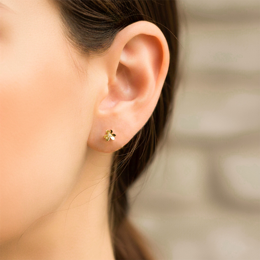Oreja de modelo usando un topito en forma de flor trébol en oro amarillo de 18 quilates de Joyería Caracas.