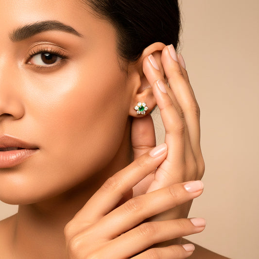 Oreja de modelo usando un topito en forma de flor con Esmeralda en el centro y cristales alrededor de Joyería Caracas.