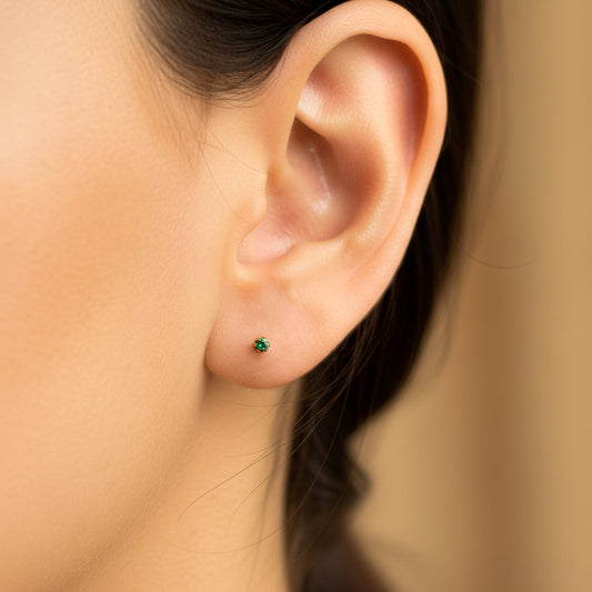 Oreja de modelo usando un topito en oro amarillo de 18 quilates con Esmeralda de 2.0mm de Joyería Caracas.