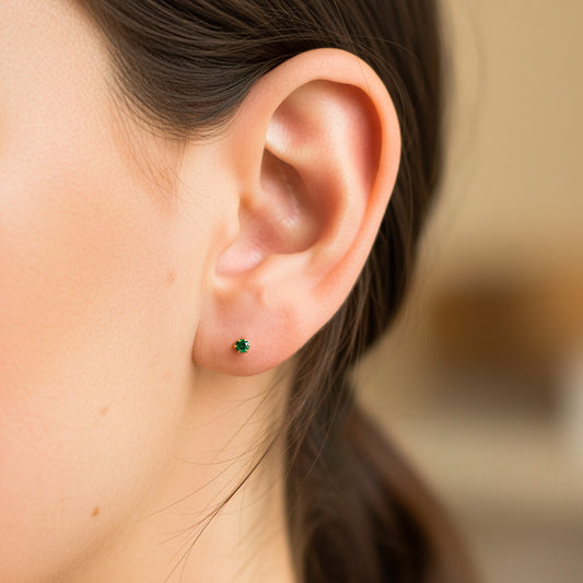 Oreja de modelo usando un topito en oro amarillo de 18 quilates con Esmeralda de Joyería Caracas.