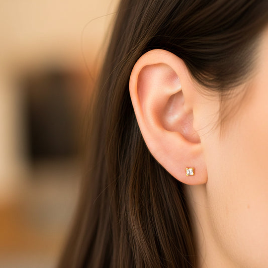 Oreja de modelo usando un topito cuadrado en oro amarillo de 18 quilates con cristales de color blanco de Joyería Caracas.