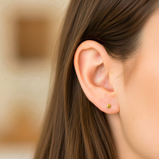 Oreja de modelo usando un topito en forma de grano de café en oro amarillo de 18 quilates de Joyería Caracas.