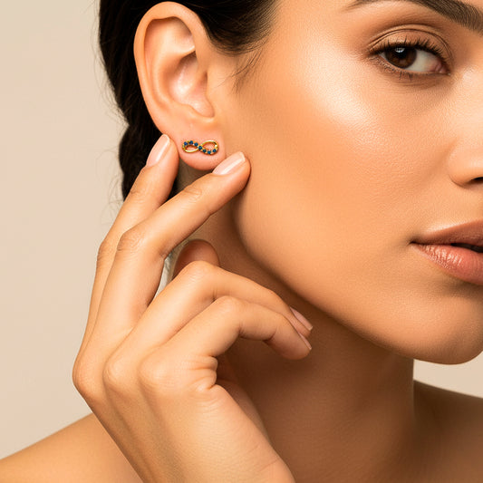 Oreja de modelo usando un topito en forma de infinito en oro amarillo de 18 quilates con cristales de color azul de Joyería Caracas.