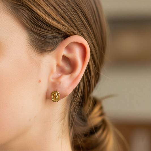Oreja de modelo usando un topito de la Virgen de la Milagrosa en oro amarillo de 18 quilates de Joyería Caracas.