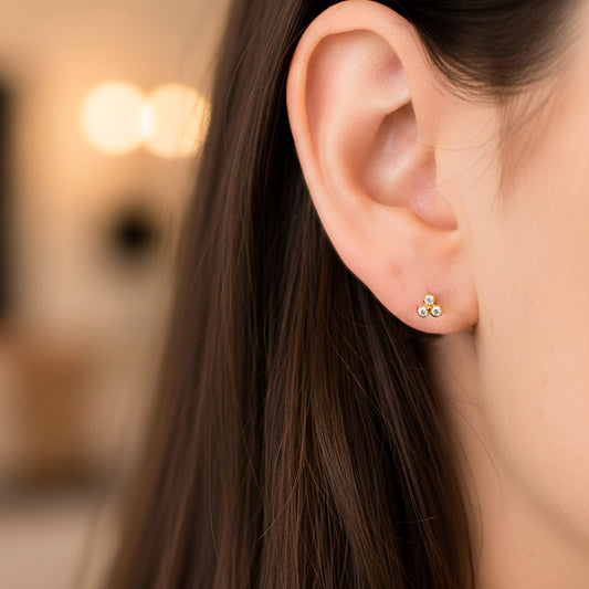 Oreja de modelo usando un topito en forma de flor mini en oro amarillo de 18 quilates con cristales de color blanco de Joyería Caracas.