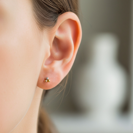 Oreja de modelo usando un topito en forma de mini flor de loto 3 oros de 18 quilates de Joyería Caracas.