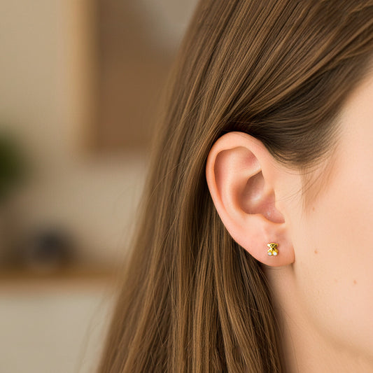 Oreja de modelo usando un topito en forma de osito en oro amarillo de 18 quilates con cristal de color blanco de Joyería Caracas.