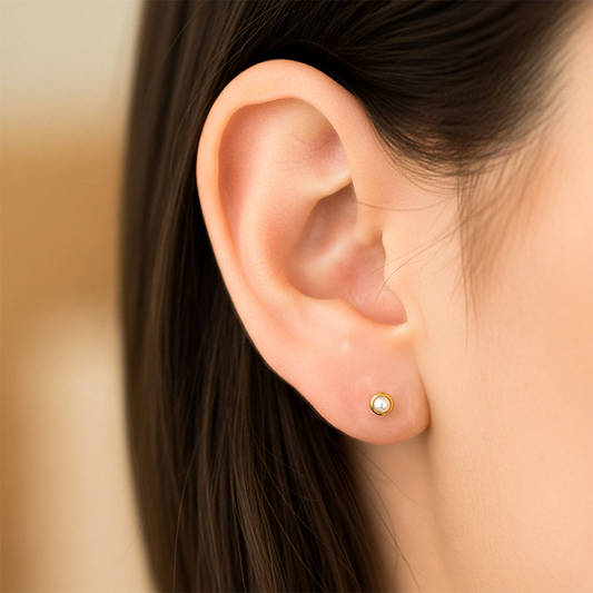 Oreja de modelo usando unos topitos biselados en oro amarillo de 18 quilates con media perla de Joyería Caracas.