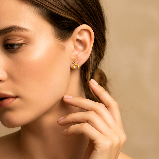 Oreja de modelo usando un topito en forma de perrito en oro amarillo de 18 quilates de Joyería Caracas.