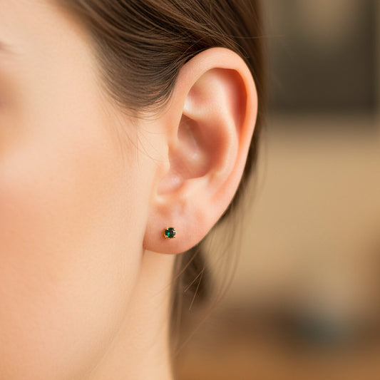 Oreja de modelo usando un topito en oro amarillo de 18 quilates con cristal verde de Joyería Caracas.