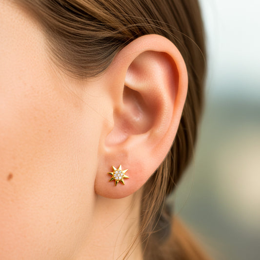 Oreja de modelo usando un topito en forma de sol en oro amarillo de 18 quilates con cristales de color blanco de Joyería Caracas.