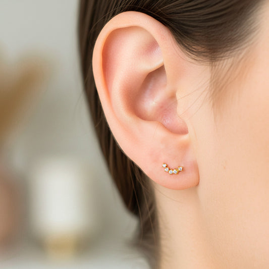 Oreja de modelo usando un topito caterpillar en oro amarillo de 18 quilates con cristales de Joyería Caracas.