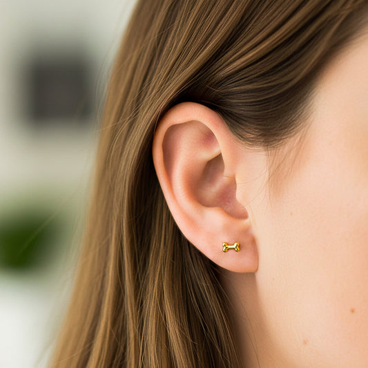 Oreja de modelo usando un topito en forma de hueso en oro amarillo de 18 quilates de Joyería Caracas.