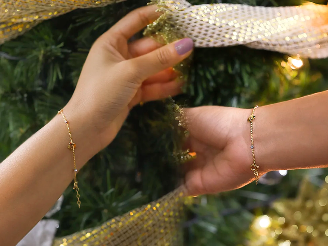 Dos manos con pulseras arreglando un árbol navideño
