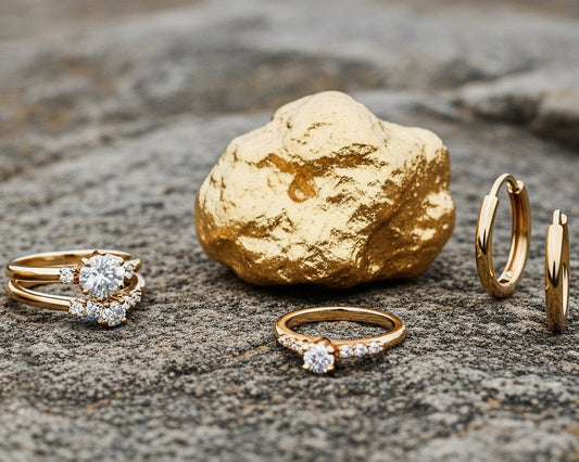 Imagen donde se logra percibir una pepita de oro, anillos de solitario con cristales de color blanco y candongas en oro amarillo de 18 quilates.