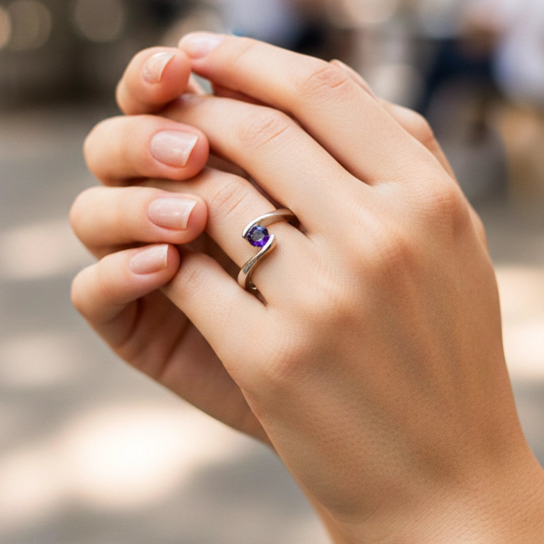Mano de una modelo usando un anillo en oro blanco con cristal purpura de Joyería Caracas.