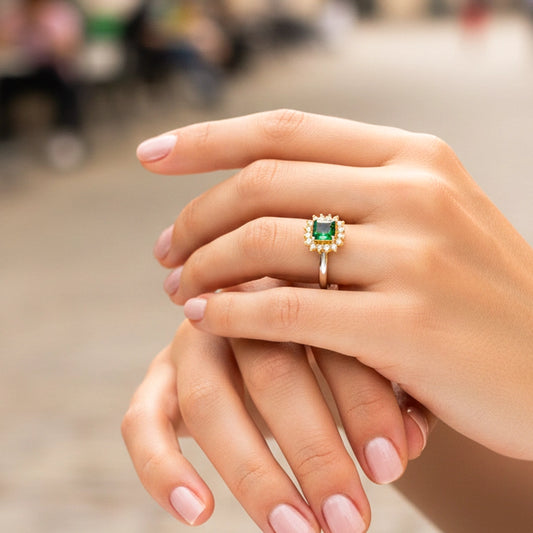 Mano de una modelo usando un anillo en oro amarillo con cristal verde y blancos de Joyería Caracas.