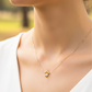 Cuello de modelo usando una cadena con un dije en forma de corona en oro amarillo de 18 quilates con cristales de Joyería Caracas.