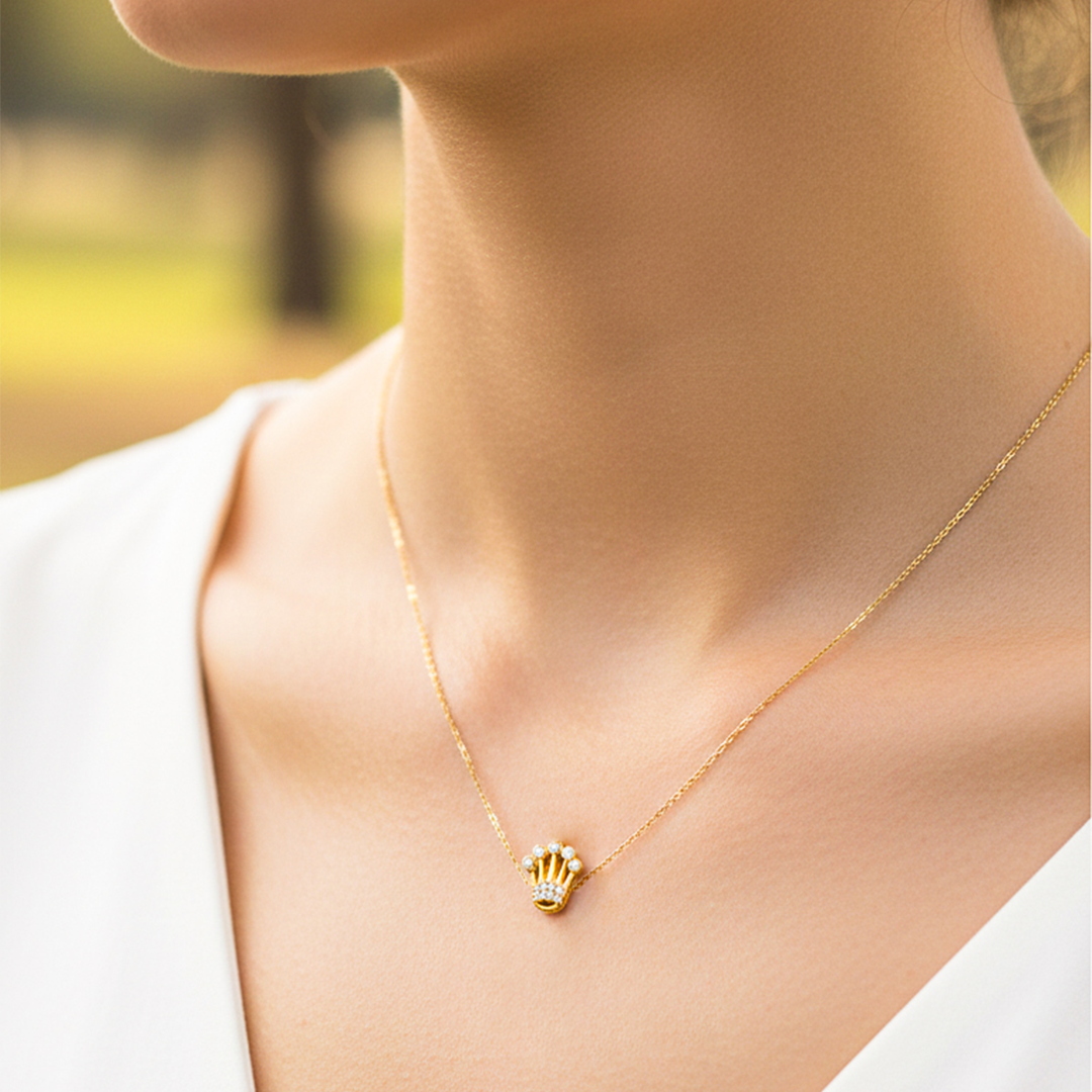 Cuello de modelo usando una cadena con un dije en forma de corona en oro amarillo de 18 quilates con cristales de Joyería Caracas.