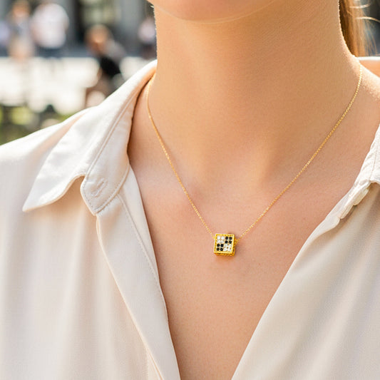 Cuello de modelo usando una cadena con un dije en forma de dado en oro amarillo de 18 quilates de Joyería Caracas.