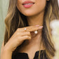 Mano de mujer con anillo en oro amarillo de 18 quilates con cristal de color blanco en el centro y cristales de color blanco alrededor.