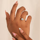 Mano de mujer con anillo inspirado en las palmeras de Miami, en oro blanco de 18 quilates con cristales de color blanco alrededor y celeste en el centro.