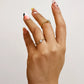 Mano de mujer con anillo en oro amarillo de 18 quilates con cristal de color blanco en el centro y cristales de color blanco, hecho en Joyería Caracas. 