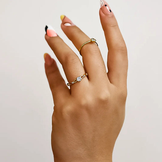 Mano de mujer con anillo en oro amarillo de 18 quilates con cristal de color blanco en el centro y cristales de color blanco, hecho en Joyería Caracas. 